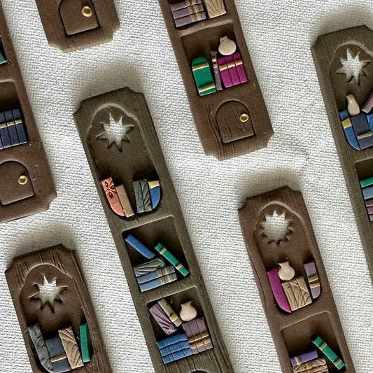Set of handmade polymer clay bookmarks shaped like miniature library shelves with a star cutout, in a Colorful Gray palette.