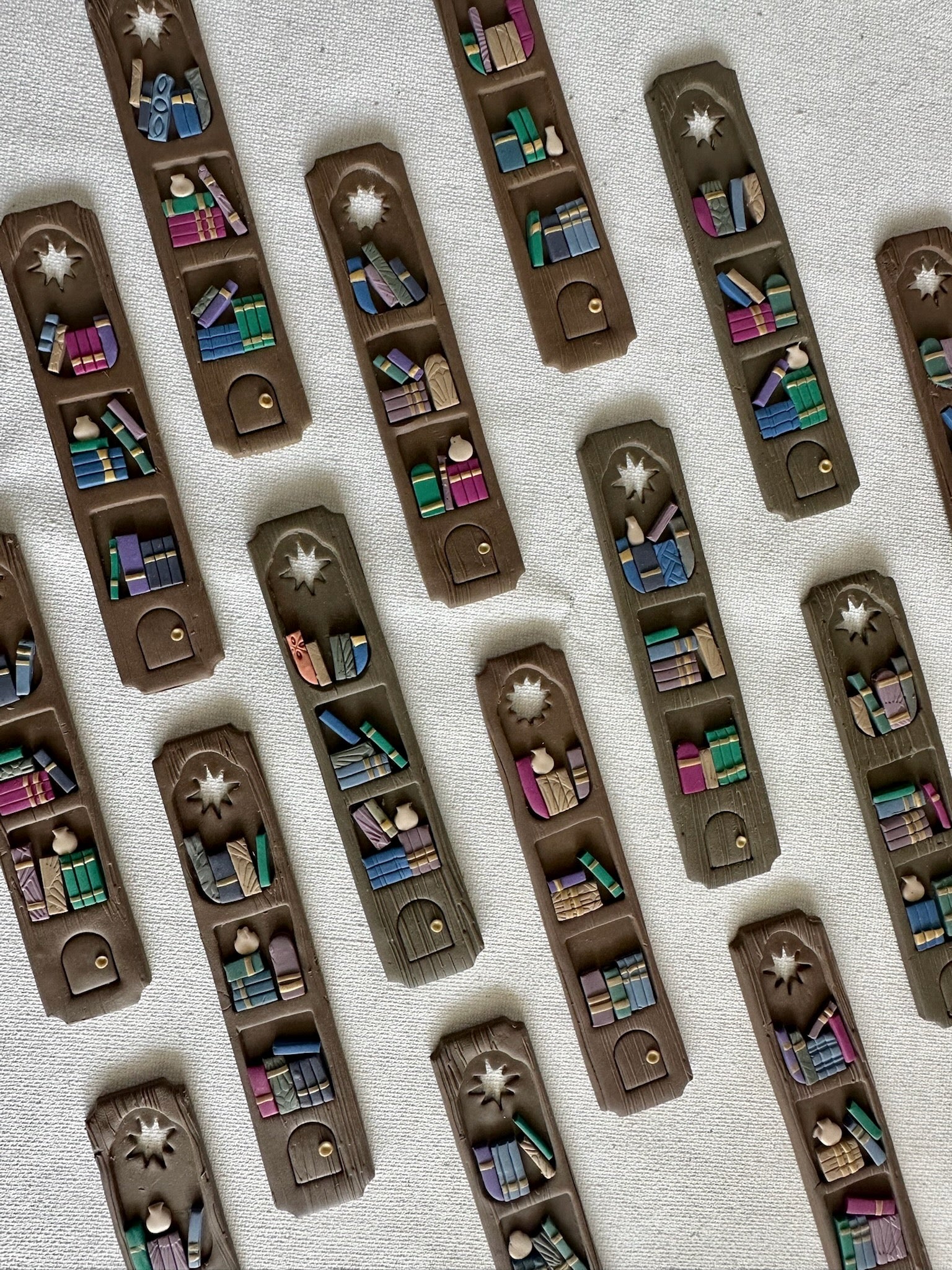 Set of handmade polymer clay bookmarks shaped like miniature library shelves with a star cutout, in a Colorful Gray palette.