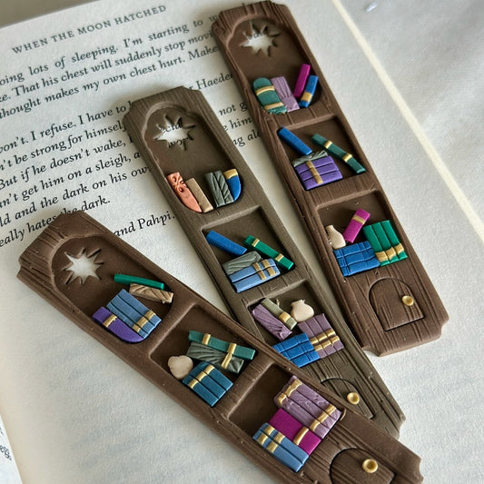 Set of handmade polymer clay bookmarks shaped like miniature library shelves with a star cutout, in a Colorful Gray palette.